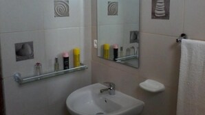 Une salle de bain avec un lavabo, un miroir et un porte-serviettes.