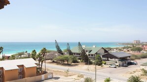 A coastal hotel with a view of the ocean, a parking area, and a road leading to the beach. - Lovely Sea View,eagle Beach, Oasis Condominium Wifi (Oranjestad)