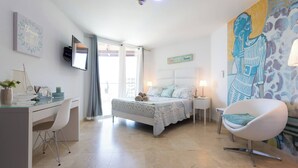 A bedroom with a bed, desk, chair, and artwork on the walls. - Lovely Sea View,eagle Beach, Oasis Condominium Wifi (Oranjestad)