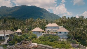 A resort with multiple buildings, a swimming pool, and a mountainous backdrop.