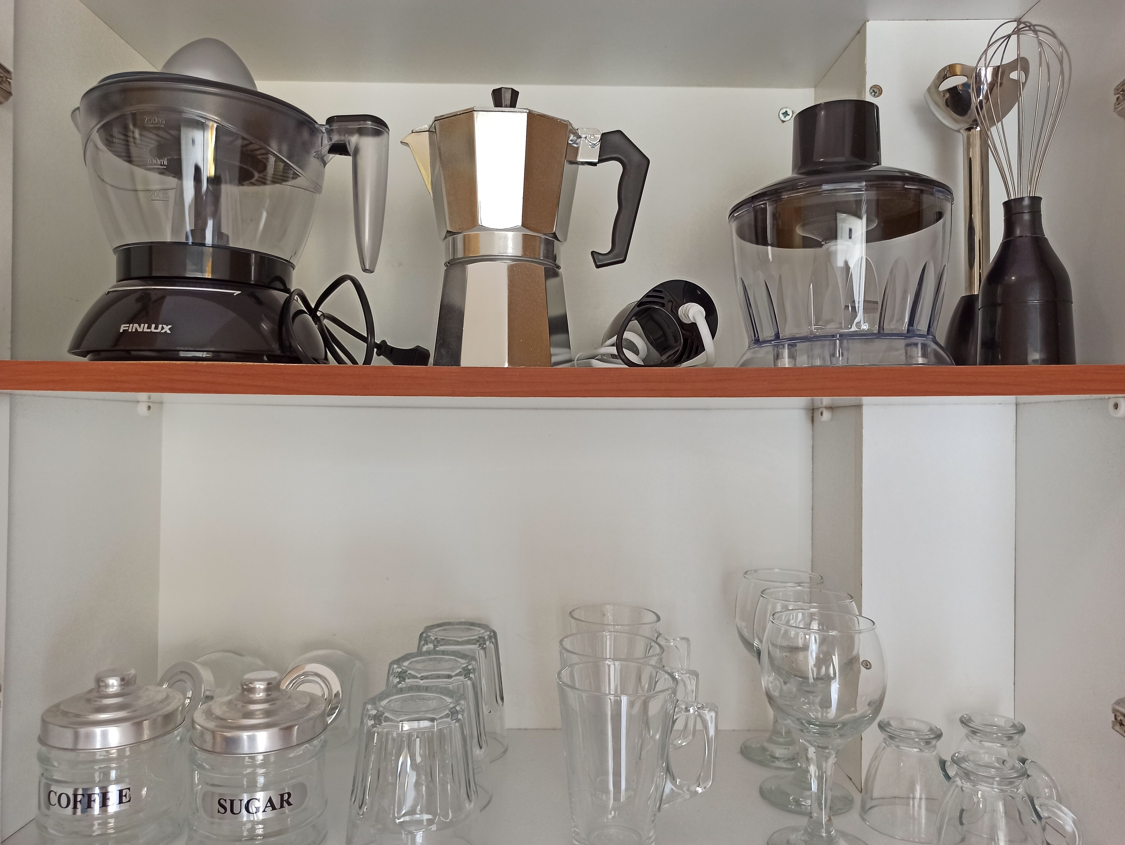 Una estantería en la cocina con electrodomésticos y recipientes de vidrio.