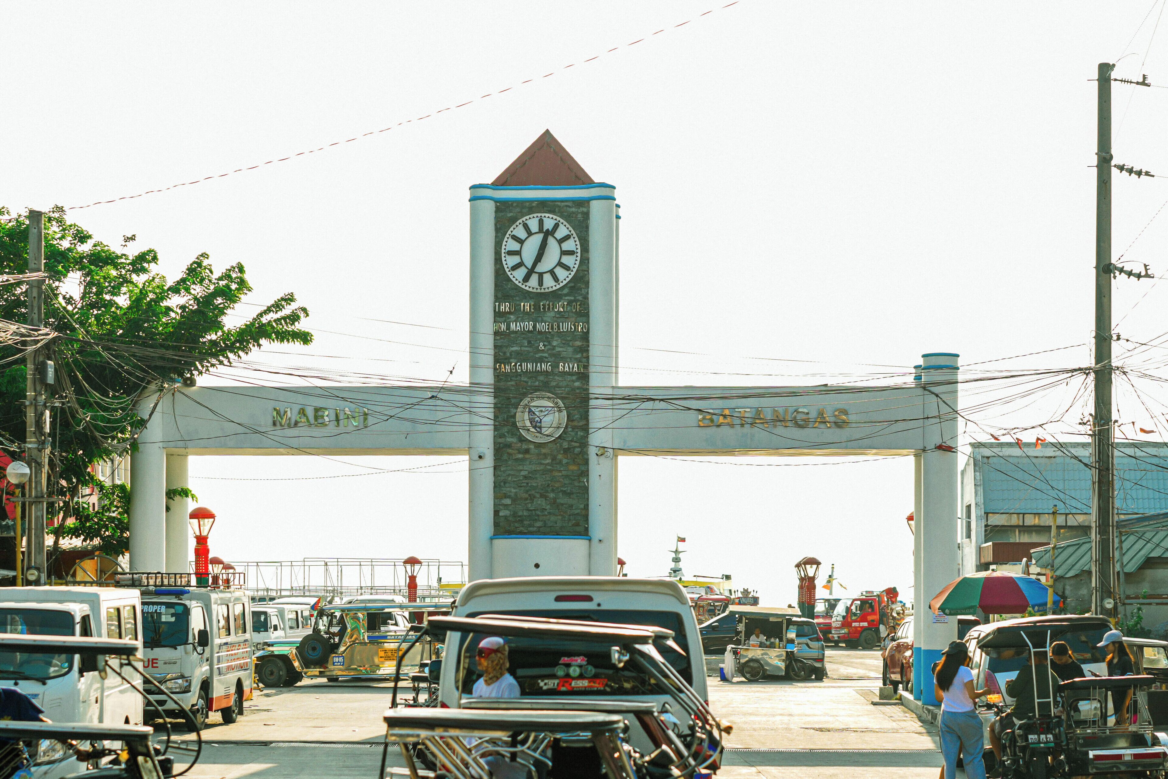 A busy toll plaza with a clock tower, vehicles, and a pedestrian crossing.