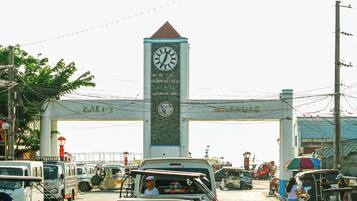 A busy toll plaza with a clock tower, vehicles, and a pedestrian crossing.
