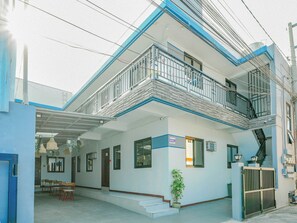 A two-story building with a balcony, a covered entrance, and a gated entrance. - Manzil Anilao Cosy 2 Bedroom Apartment U1 (Mabini)