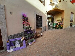 A narrow alley with a building numbered 35, potted plants, and a small table with chairs.