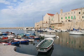 A harbor with multiple boats docked, a stone building with a red roof, and a clear sky. - Giovinazzo Historic Apulia (Giovinazzo)