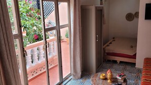 A room with a bed, a sofa, a TV, and a small table with decorative items.
