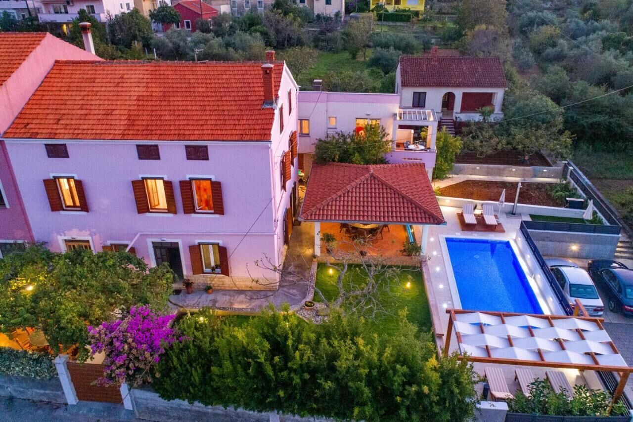 A two-story house with a swimming pool, outdoor seating, and a garden.
