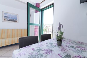 Relax on the balcony with a view of the surrounding buildings, featuring a sofa and a potted plant.