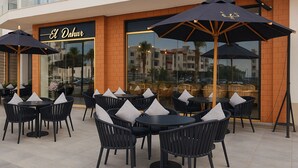 An outdoor seating area with black chairs and tables, umbrellas, and a sign reading "El Dah". - Chalet Porto Said Tourist Resort (Al-Manasrah)