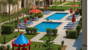 A resort pool area with a clear view of the ocean, a children's play structure, and multiple lounge chairs and umbrellas. - Luxurious Chalet With Garden View in Port Said Overnorate (Al-Manasrah)