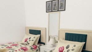 A double bed with floral bedding, a bedside table with a lamp, and a wall-mounted picture frame. - Luxurious Chalet With Pool Access in Port Said Governorate (Al-Manasrah)