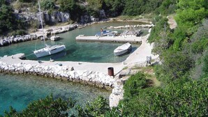 A coastal marina with boats docked, surrounded by rocky terrain and greenery. - Beachfront Holiday House Žal (Preko)