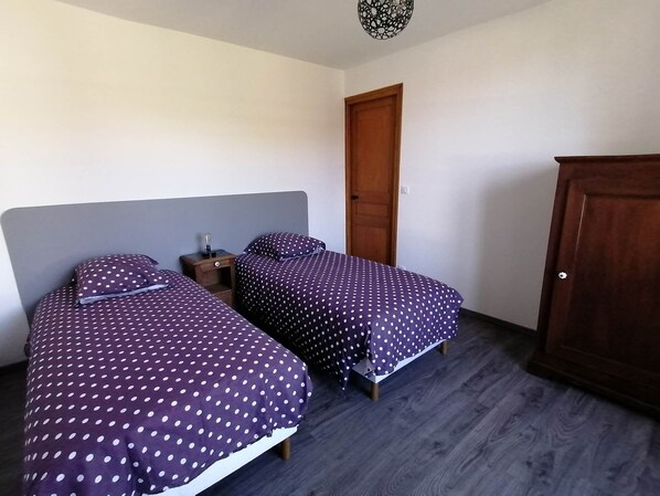 Ein Schlafzimmer mit zwei Betten, einem Holzschrank und einem Nachttisch mit Lampe.