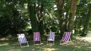 Three beach chairs with striped cushions in a grassy area surrounded by trees. - Gîte de la Gare (Esclavolles-Lurey)