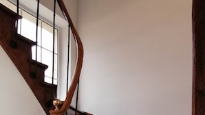 Eine Holztreppe mit geschwungener Handlauf und einer Messingzierde oben.