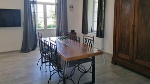 A dining area with a wooden table, chairs, and a cabinet. - Gîte de la Gare (Esclavolles-Lurey)