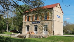 A two-story building with a red-tiled roof, a sign reading "LIBRE-LOUIS," and a stone staircase leading to the entrance. - Gîte de la Gare (Esclavolles-Lurey)