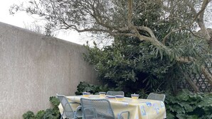 An outdoor table set with chairs, a concrete wall, and dense foliage in the background.
