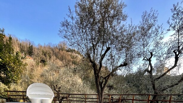 A clear pool with a wooden deck and a white cushioned seating area. - Family villa with pool (Campania)