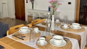 A dining area with a table set for four, surrounded by chairs, with a decorative wall piece above. - Family villa with pool (Campania)
