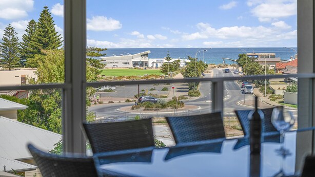 A view from a window overlooking a coastal area with a roundabout, buildings, and a clear sky.