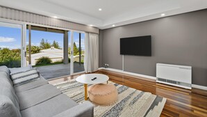 A modern living room with a grey sofa, a round coffee table, and a television mounted on the wall.