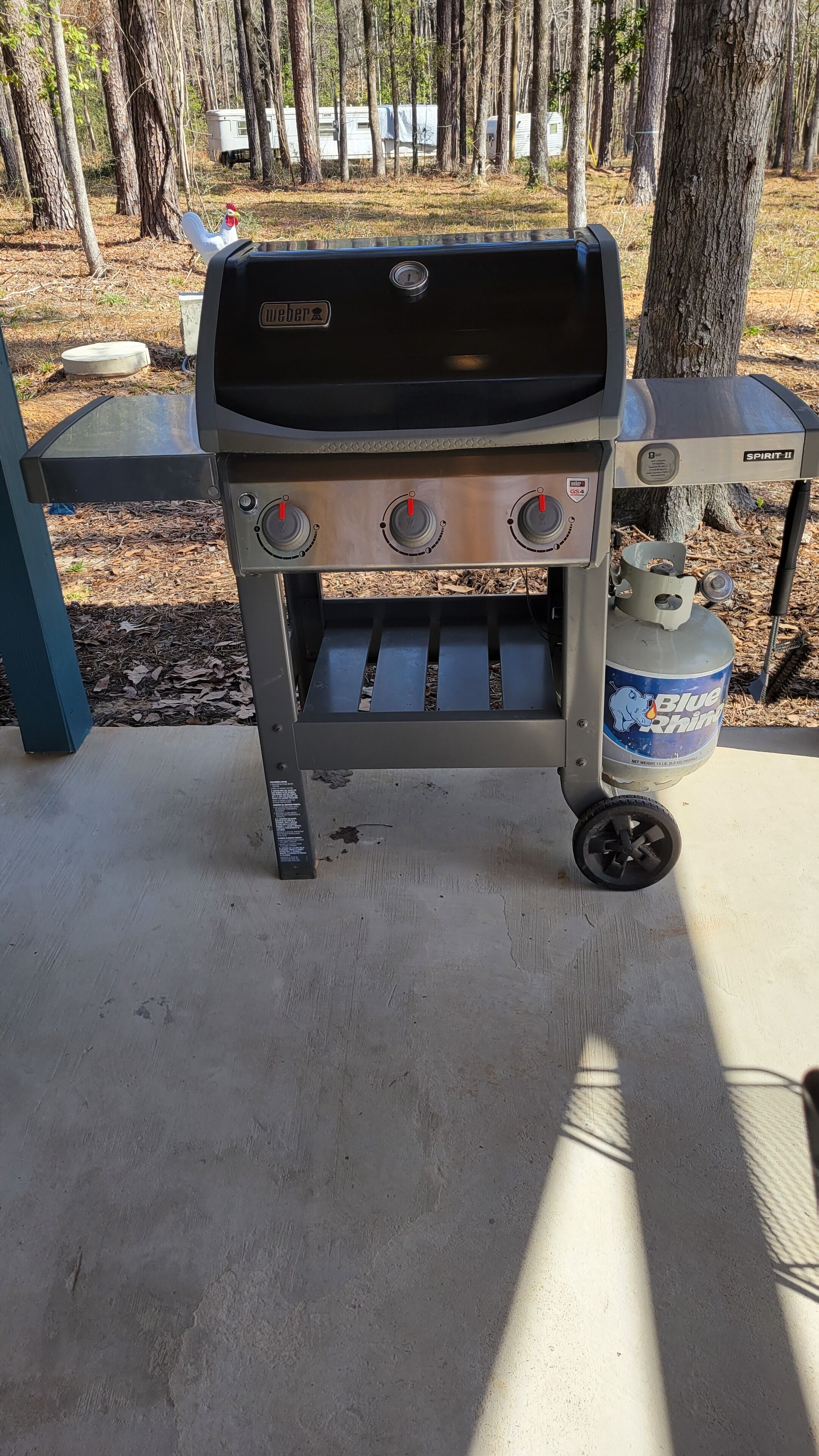 A portable gas grill with three burners and a propane tank.