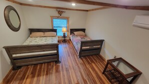 A bedroom with two wooden beds, a mirror, a lamp, and a window with blinds. - Cabin on a Secluded Cove -- READ DESCRIPTION REGARDING SAM RAYBURN WATER LEVEL (Broaddus)