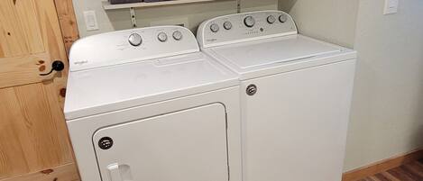 A laundry room with a washer and dryer, wooden flooring, and a cabinet above the appliances.