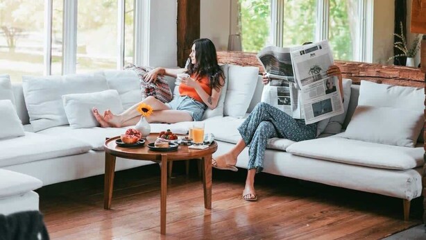 A room with a wooden ceiling, large windows, a white sofa, and a coffee table with food and drinks. - Glasco Woodstock - 16 Acres with Mountain View. (Saugerties)