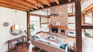 A spacious living area with a brick fireplace, wooden beams, and a large mirror on the wall. - Glasco Woodstock - 16 Acres with Mountain View. (Saugerties)