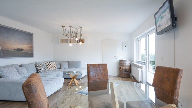 Ein modernes Wohnzimmer mit einem Couchtisch mit Glasplatte, einem Sofa und zwei braunen Sesseln.
