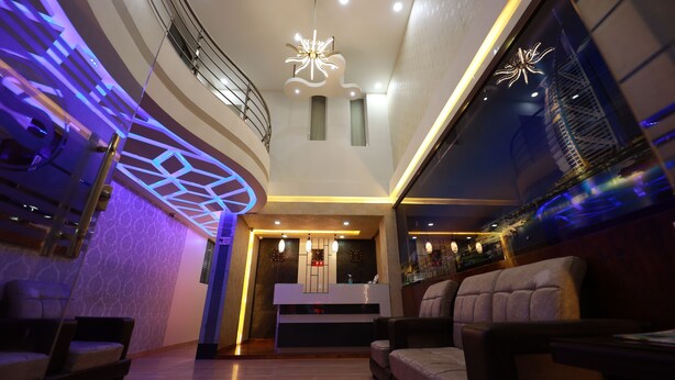 Un hall d’hôtel moderne avec un comptoir d’accueil, un espace salon et des luminaires décoratifs au plafond.