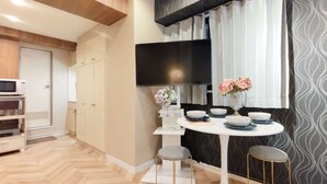 A compact kitchen with a modern design, featuring a white countertop, a built-in oven, and a flat-screen TV mounted above the counter. - 4 min walk from the nearest station in the most prosperous town in Shinjuku City Apartment room (新宿区)