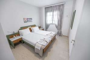 Una cama doble con ropa blanca, una mesita de noche con lámpara y un cuadro en la pared.