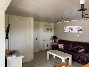 A living room with a brown leather sofa, a white coffee table, and a white cabinet.