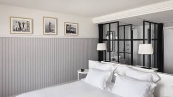 Una habitación de hotel moderna con una cama grande, una mesita de noche pequeña, un espejo y tres cuadros en la pared.