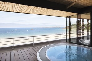 A modern balcony with a wooden floor, a glass railing, and a view of the sea. - Grand Hôtel Perros-Guirec (Perros-Guirec)