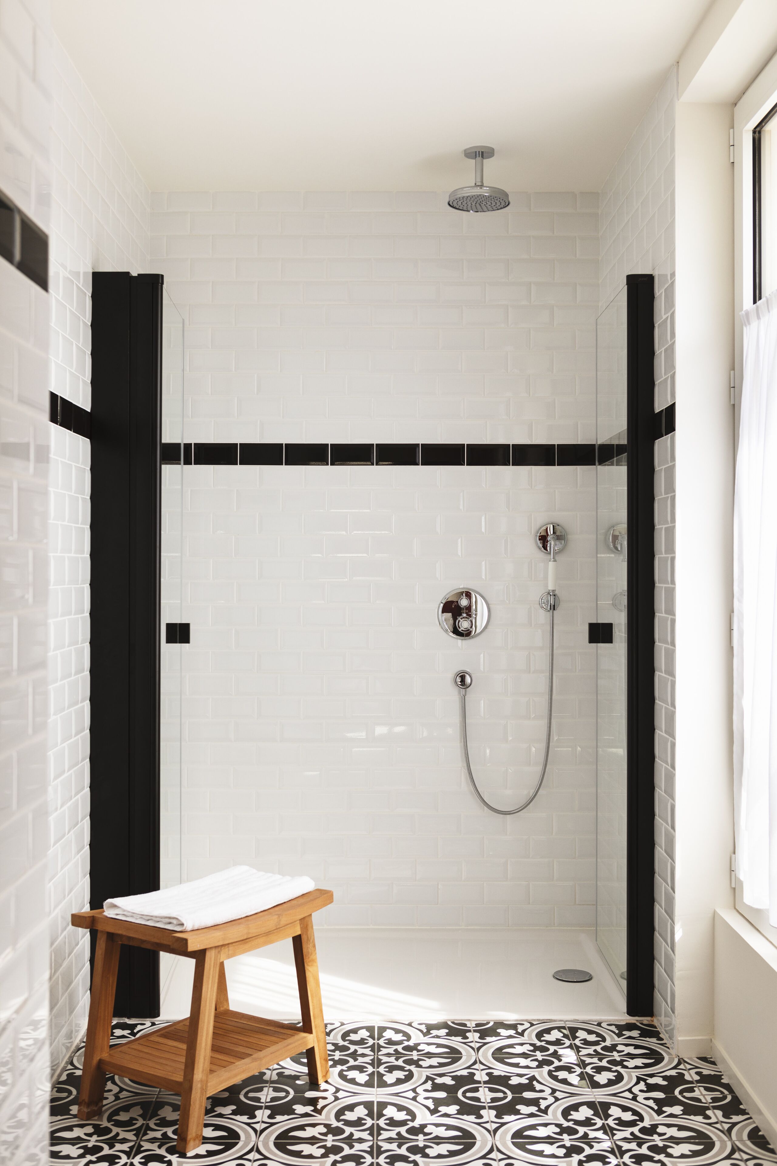 A small, enclosed shower area with white tiled walls and a black-tiled floor.