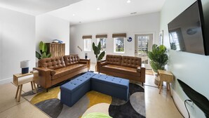 Un salon moderne avec deux canapés en cuir marron, un canapé d’angle bleu et un grand téléviseur à écran plat fixé au mur.