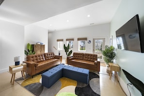 Relax in this stylish living room with two comfortable sofas, a matching ottoman, and a large flat-screen TV.