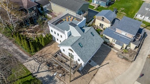 Two-story house surrounded by a well-maintained lawn and trees, with a driveway and garden area.