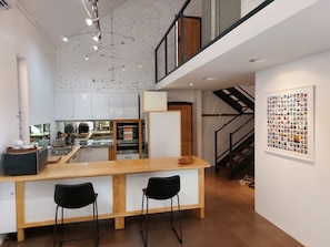 Una cocina moderna con armarios blancos, una isla de madera y taburetes negros.