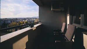 Un balcon donnant sur un paysage urbain, une fenêtre et un climatiseur fixé au mur.