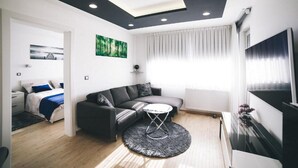 Un salon moderne avec un canapé, une petite table ronde, un téléviseur et un tableau accroché au mur.