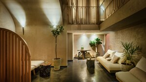 A spacious living area with a high ceiling, a wooden staircase, and a seating area with a sofa and chairs. - Pixel Dizengoff Square - Smart Hotel by Loginn Tel Aviv (Tel Aviv)