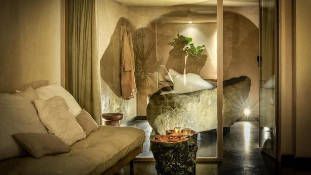 A modern interior with a sofa, a table with drinks, a plant, and a large rock. - Pixel Dizengoff Square - Smart Hotel by Loginn Tel Aviv (Tel Aviv)