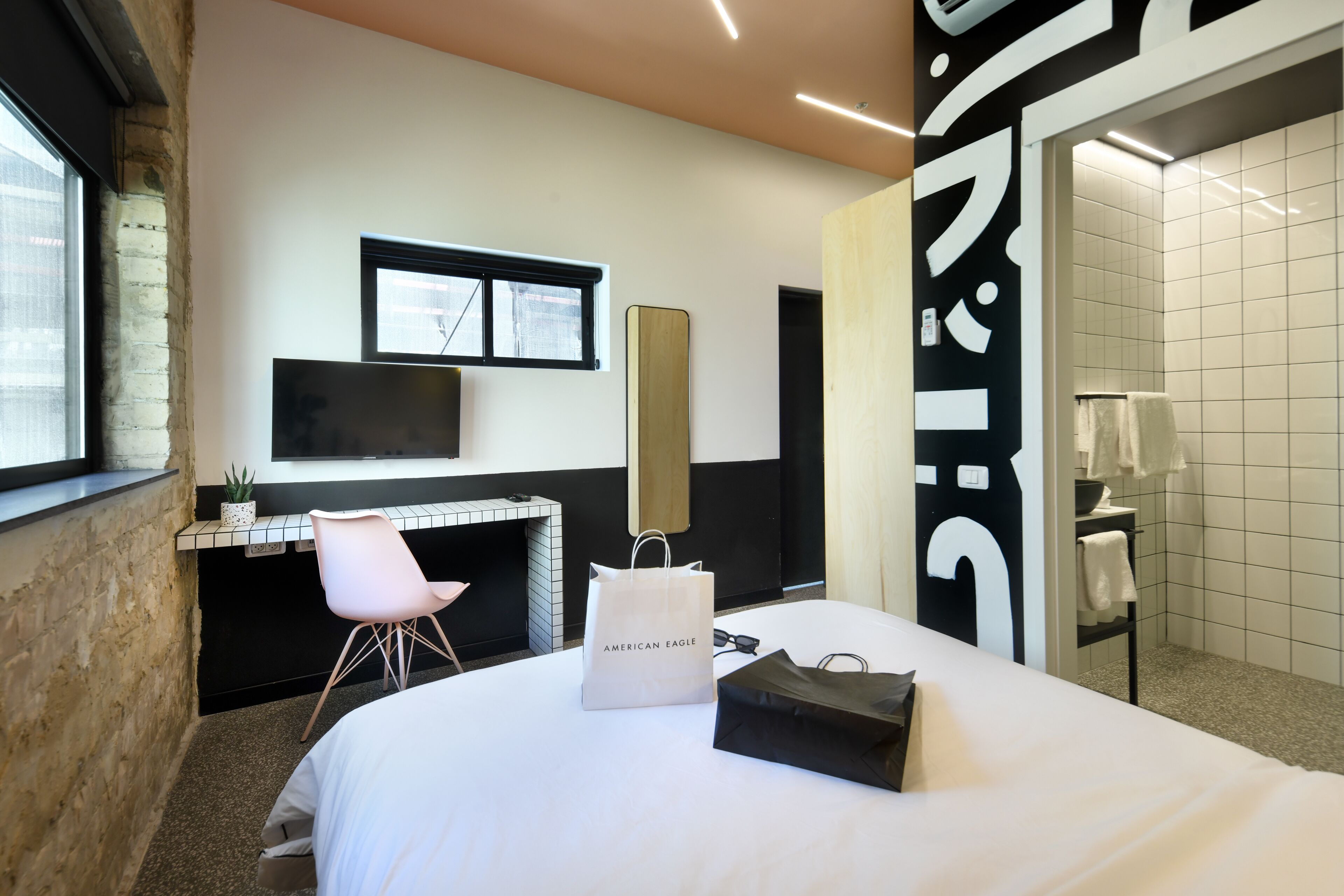 Une chambre d’hôtel moderne, dotée d’un grand lit, d’un bureau, d’une chaise et d’une salle de bain visible à travers une porte ouverte.