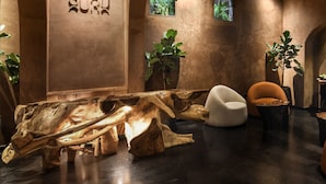 A modern interior with a wooden sculpture centerpiece, a white chair, and a small table with a plant. - Pixel Dizengoff Square - Smart Hotel by Loginn Tel Aviv (Tel Aviv)